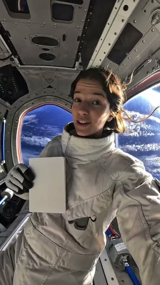 A presenter floating inside a spacecraft above Earth