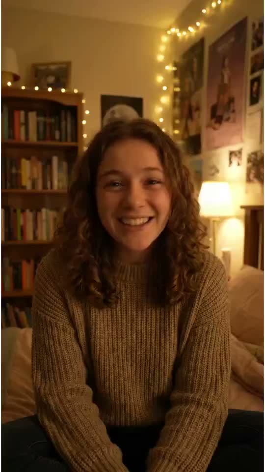 A smiling presenter seated in a warmly lit room